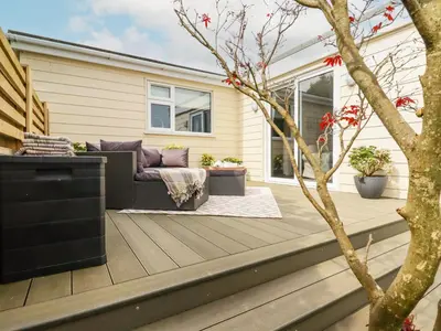 a patio with a couch and a tree at Badgers Sett in Tintagel