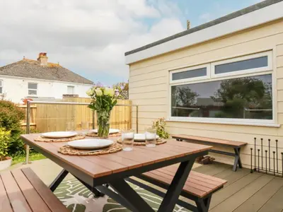 a patio with a wooden table and benches at Badgers Sett in Tintagel