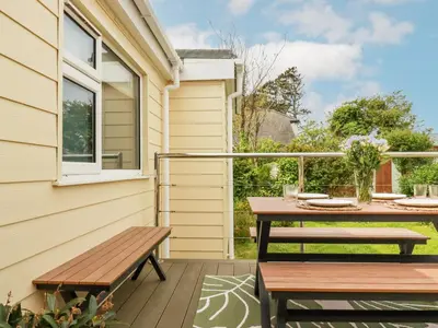 a patio with a wooden table and benches at Badgers Sett in Tintagel