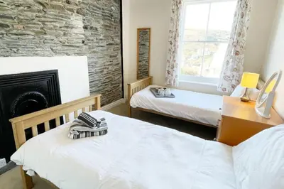a bedroom with two beds and a fireplace at Morwenna, Port Isaac Bay Holidays in Port Isaac