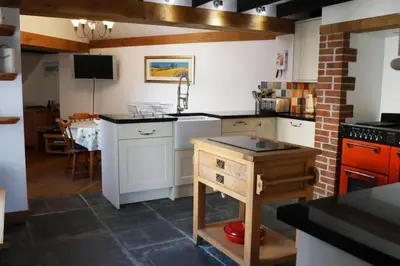 a kitchen with white cabinets and a brick wall at Morwenna, Port Isaac Bay Holidays in Port Isaac