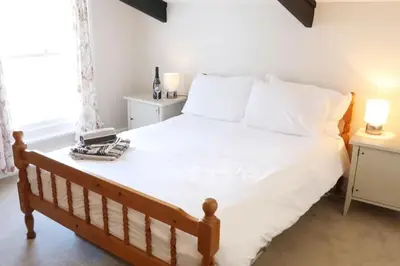 a bedroom with a bed with white sheets and a window at Morwenna, Port Isaac Bay Holidays in Port Isaac