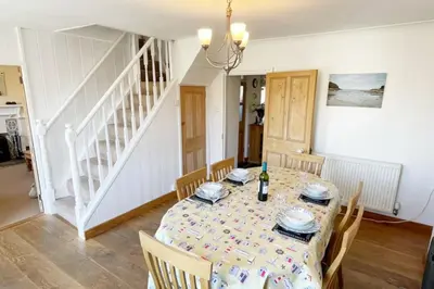 a dining room with a table and chairs and a staircase at Morwenna, Port Isaac Bay Holidays in Port Isaac