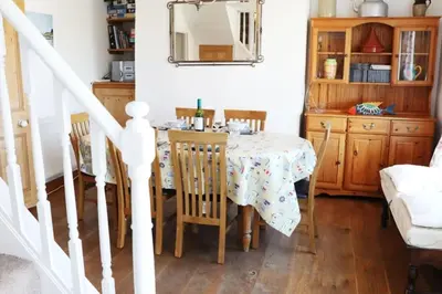 a dining room with a table with chairs and a mirror at Morwenna, Port Isaac Bay Holidays in Port Isaac