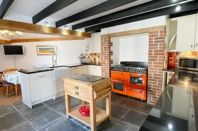 a kitchen with white cabinets and a brick wall at Morwenna, Port Isaac Bay Holidays in Port Isaac