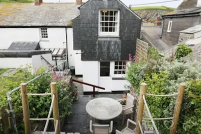 a small patio with a table and chairs in front of a house at Waypast, Port Isaac Bay Holidays in Port Isaac