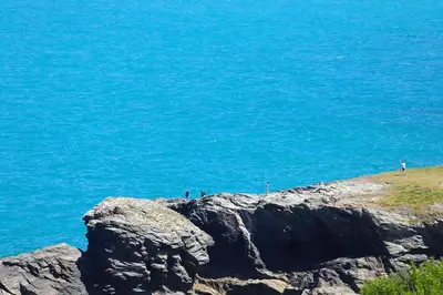 a group of people standing on a cliff near the ocean at Cockleshell, Port Isaac Bay Holidays in Port Isaac