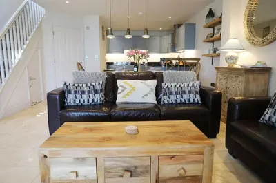a living room with a leather couch and a coffee table at Cockleshell, Port Isaac Bay Holidays in Port Isaac