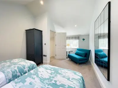a bedroom with two beds and a blue chair at Cockleshell, Port Isaac Bay Holidays in Port Isaac