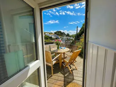 a balcony with a table and chairs on a deck at The Rockies, Port Isaac Bay Holidays in Port Isaac
