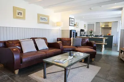a living room with brown leather couches and a table at The Rockies, Port Isaac Bay Holidays in Port Isaac