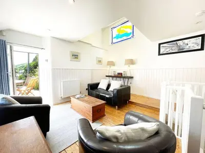 a living room with couches and a table at The Rockies, Port Isaac Bay Holidays in Port Isaac
