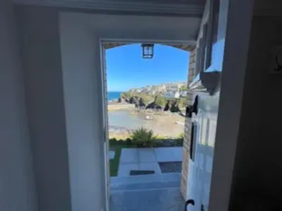 a door to a room with a view of the ocean at Folly 1, Port Isaac Bay Holidays in Port Isaac
