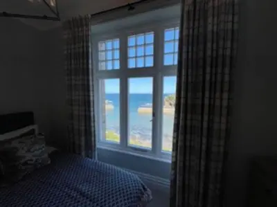 a bedroom with a window with a view of the ocean at Folly 1, Port Isaac Bay Holidays in Port Isaac