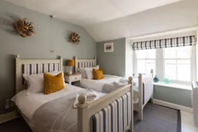 a bedroom with two beds and a window at Kicker Cottage, Port Isaac Bay Holidays in Port Isaac