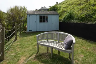 a bench with a pillow sitting in a yard at Kicker Cottage, Port Isaac Bay Holidays in Port Isaac