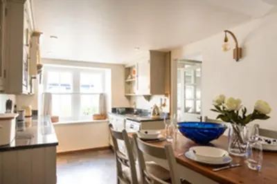 a kitchen with a wooden table with a blue bowl on it at Kicker Cottage, Port Isaac Bay Holidays in Port Isaac