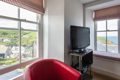 a living room with a red chair and a television at Upper Deck, Port Isaac Bay Holidays in Port Isaac