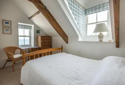 a bedroom with a bed and a chair and a window at Upper Deck, Port Isaac Bay Holidays in Port Isaac