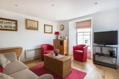 a living room with a couch and a tv and red chairs at Upper Deck, Port Isaac Bay Holidays in Port Isaac