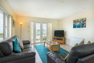 a living room with two leather couches and a television at Sea Gem, Port Isaac Bay Holidays in Port Isaac