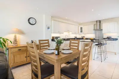 a kitchen and dining room with a wooden table and chairs at Sea Gem, Port Isaac Bay Holidays in Port Isaac