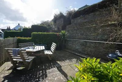 a patio with two wooden chairs and a table at Scuppers, Port Isaac Bay Holidays in Port Isaac