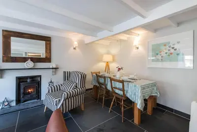 a dining room with a table and chairs and a fireplace at Scuppers, Port Isaac Bay Holidays in Port Isaac
