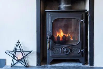 a black fireplace with a fire in it at Scuppers, Port Isaac Bay Holidays in Port Isaac