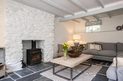 a living room with a stone fireplace and a couch at Windlass, Port Isaac Bay Holidays in Port Isaac
