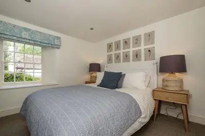 a bedroom with a bed and two lamps and a window at Windlass, Port Isaac Bay Holidays in Port Isaac