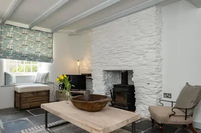 a living room with a stone fireplace and a wooden bowl on a table at Windlass, Port Isaac Bay Holidays in Port Isaac