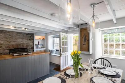 a dining room with a table and a fireplace at Windlass, Port Isaac Bay Holidays in Port Isaac