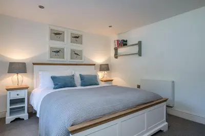 a bedroom with a large bed with blue pillows at Windlass, Port Isaac Bay Holidays in Port Isaac