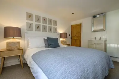 a bedroom with a bed with a blue comforter at Windlass, Port Isaac Bay Holidays in Port Isaac