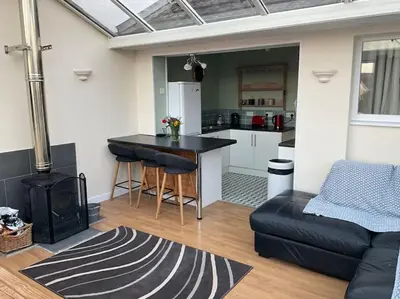 a kitchen and living room with a table and a stove at Comfy and welcoming 2 bedroom Annex. in Padstow