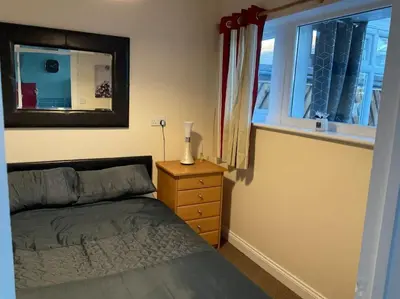 a bedroom with a bed and a mirror and a window at Comfy and welcoming 2 bedroom Annex. in Padstow