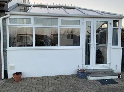 a white house with a conservatory with windows at Comfy and welcoming 2 bedroom Annex. in Padstow