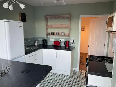 a kitchen with white cabinets and a black counter top at Comfy and welcoming 2 bedroom Annex. in Padstow