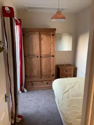 a bedroom with a bed and a wooden cabinet at Comfy and welcoming 2 bedroom Annex. in Padstow