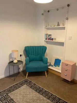 a living room with a blue chair and a table at Comfy and welcoming 2 bedroom Annex. in Padstow