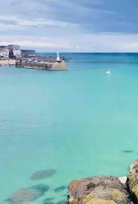 a large body of water with a lighthouse in the distance at The Little Snug in St Ives in St Ives