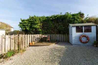 a small shed sitting next to a fence at Ebrel, Port Isaac Bay Holidays in Port Isaac