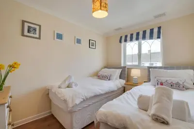 a bedroom with two beds and a window at Ebrel, Port Isaac Bay Holidays in Port Isaac
