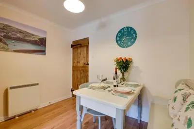 a dining room with a table and a clock on the wall at Ebrel, Port Isaac Bay Holidays in Port Isaac