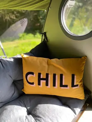 a pillow with the word child written on it next to a window at Exclusive Use Riverside Landpods at Wildish Cornwall in Bodmin