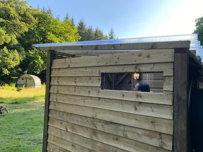 a man looking out of a window in a out house at Exclusive Use Riverside Landpods at Wildish Cornwall in Bodmin