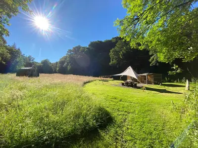a tent in a field with the sun in the sky at Exclusive Use Riverside Landpods at Wildish Cornwall in Bodmin