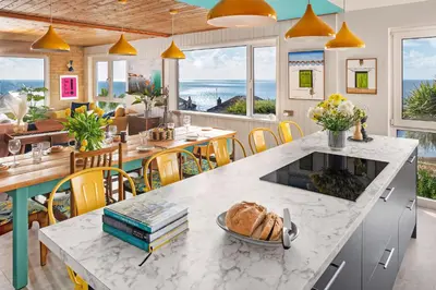 a kitchen and dining room with a table with bread on it at Sunset Beach House Porthleven in Porthleven