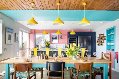 a kitchen and dining room with a large wooden table and chairs at Sunset Beach House Porthleven in Porthleven